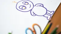 Boceto colorido del personaje de dibujos animados sobre papel con lápices de colores en el lado.
