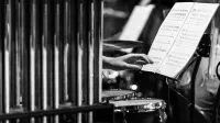 Imagen monocromática de una mano que busca partituras en una configuración de percusión.