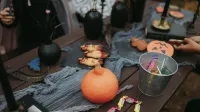 Mesa rústica de Halloween con golosinas, calabaza, dulces y decoraciones espeluznantes.