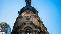 Vista de ángulo bajo de la icónica cúpula del edificio de la Bolsa de Valores de Santiago contra un cielo azul claro.