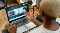 Una persona participa en una videollamada en su computadora portátil en un ambiente relajado en el hogar, fomentando la comunicación remota.