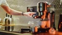 A man interacts with a touchscreen in a stylish kitchen setting, featuring modern appliances.