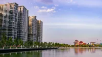 Una vista panorámica de los rascacielos urbanos junto a un tranquilo lago al atardecer.