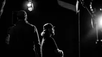 A black and white portrait of individuals in a dramatic studio setting with focused lighting.