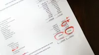 Estado financiero con anotaciones rojas sobre una mesa de madera.