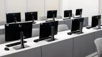 Un laboratorio de computadoras vacío con modernas configuraciones de escritorio y sillas ergonómicas.