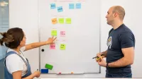 Dos profesionales que hacen una lluvia de ideas y planean proyectos en una pizarra en un entorno de oficina colaborativo.
