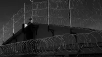 Imagen en escala de grises de cercas de alambre de púas que representan seguridad y protección.