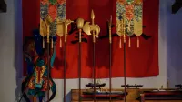 Statue of a samurai with ceremonial flags in a traditional Japanese setting.