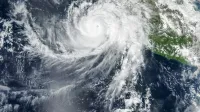 El ojo bien definido del huracán Simon se encuentra justo al lado de la costa del Pacífico de México. Algunas bandas de nubes externas de la tormenta en espiral se extienden sobre la tierra.