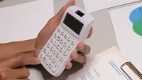 Close-up of hands using a calculator next to a company invoice, depicting a financial calculation concept.
