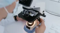Close-up of a scientist examining samples under a microscope in a laboratory setting.