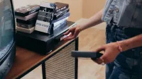 Una persona que configura una videograbadora con cintas VHS en un ambiente interior acogedor.