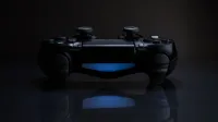 Primer plano de un controlador de juegos con una luz azul suave en un entorno oscuro.