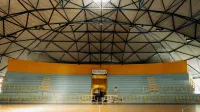 Un hombre corriendo por una cancha de baloncesto dentro de un pabellón deportivo con techo de cúpula.
