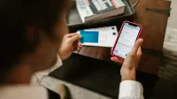Persona que realiza un pago en línea con un smartphone y una tarjeta de crédito en el interior.
