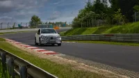 Coche deportivo camuflado conduciendo en la icónica pista de carreras de Nurburgring.