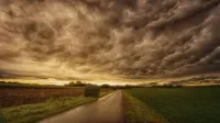 Un espectacular paisaje de campo con nubes tormentosas y un camino vacío al anochecer.