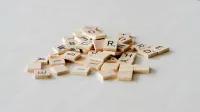 Primer plano de azulejos de letras de madera esparcidos sobre una superficie de mesa ligera, ideal para juegos de palabras.