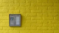 A vibrant yellow brick wall featuring a modern intercom system, ideal for security or design concepts.