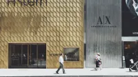 Escena de compras urbanas con tiendas de H. Stern y Armani Exchange, capturando a los peatones en un día soleado.