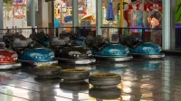 Coches vibrantes parachoques estacionados en el interior en un parque de diversiones, esperando a los jinetes.