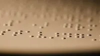 Toma macro de puntos braille en relieve en papel, ilustrando la lectura táctil para personas con discapacidad visual.