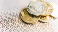 Stack of Bitcoin and Litecoin coins on a geometric textured surface, symbolizing digital finance.