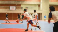 Juego de baloncesto enérgico en una cancha cubierta con jugadores en movimiento, mostrando el trabajo en equipo y la agilidad.