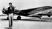 Amelia Earhart de pie frente al Lockheed Electra en el que desapareció en julio de 1937.
