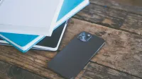 Un smartphone moderno colocado junto a una variedad de cuadernos en una superficie de madera rústica