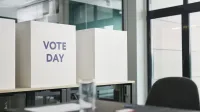 Una oficina moderna con cabinas de votación etiquetadas como "Día de votos" que indican actividad electoral.