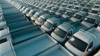 Toma aérea de varias camionetas plateadas alineadas en filas, mostrando simetría y producción industrial.