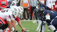 Rival football teams face off at the start of an action-packed game on the field.
