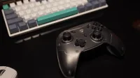 Primer plano de un controlador de juegos en un escritorio con teclado y mouse, perfecto para los jugadores.