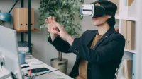 Un hombre en un entorno de oficina con auriculares de realidad virtual, interactuando con contenido de realidad virtual.