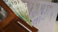 Close-up of a wallet containing Polish Zloty with a signed document in the background, representing financial transactions.