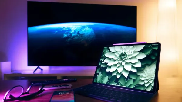 Elegante configuración de oficina en casa con dispositivos como tableta, teléfono inteligente y pantalla grande.