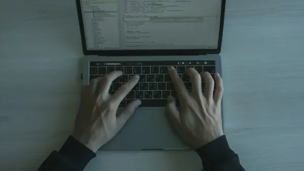 Vista cercana de un programador que codifica en una computadora portátil, mostrando el desarrollo de software moderno.