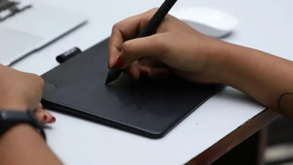 Close-up of hands using a graphic tablet with stylus for creative design, shot in Chennai, India.