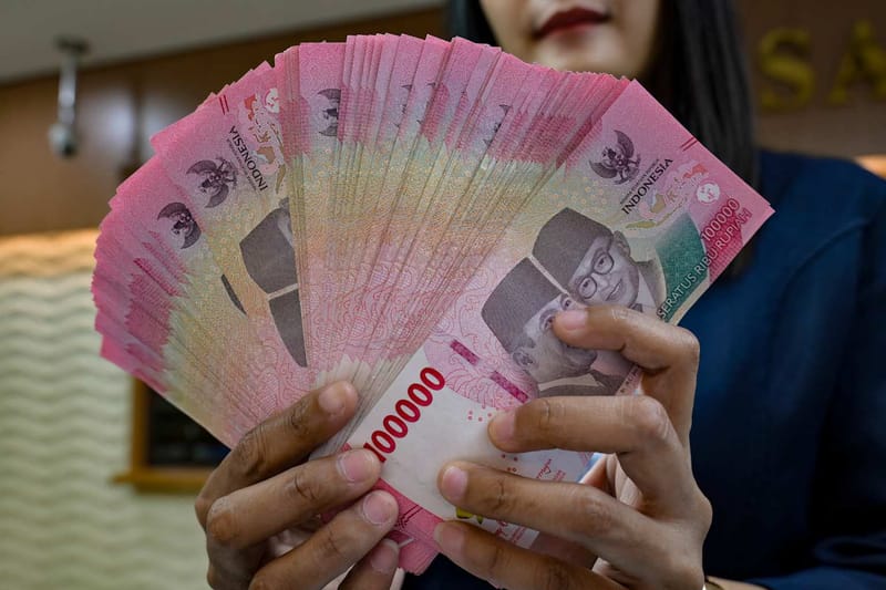 Un cambista sostiene billetes de rupia en una oficina de cambio de divisas
