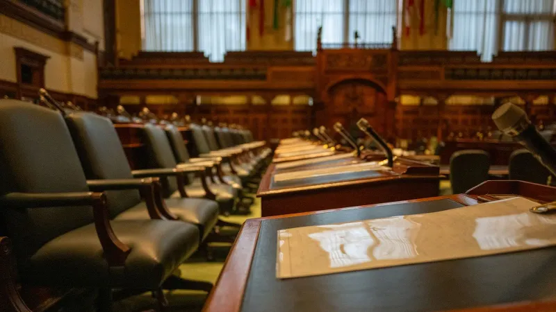 A detailed view of an empty legislative chamber with rows of desks and microphones, evoking governance.