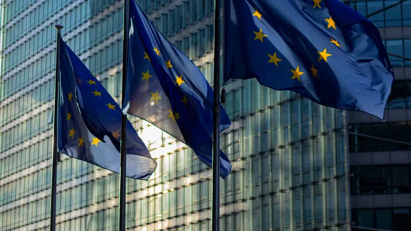 EU flags waving in front of the European Commission building in Brussels, Belgium.