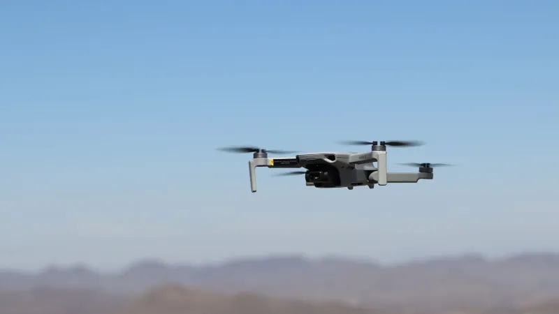 Drone flying over a desert landscape under clear blue skies.