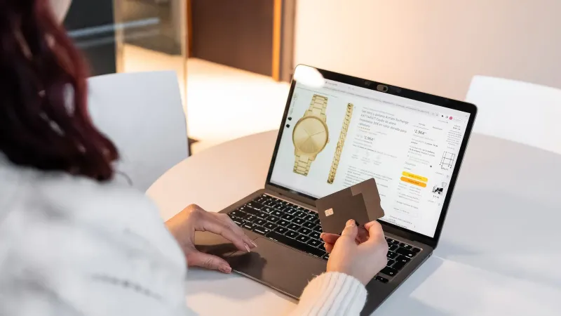 A woman making an online purchase using a laptop and credit card at home.