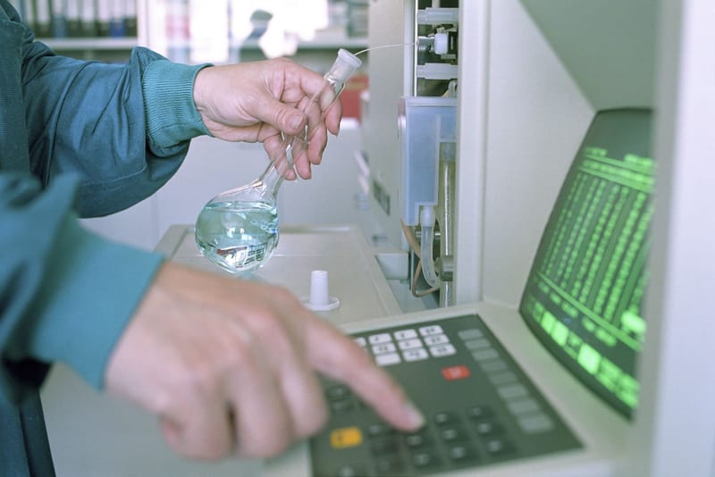 Close-up of a scientist operating lab equipment with a flask in hand.