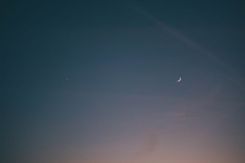 A tranquil scene of a crescent moon and star in the evening sky, evoking calmness and wonder.