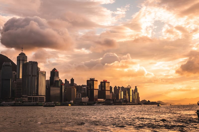 Capture of Hong Kong's skyline at sunset with dramatic clouds and waterfront view.