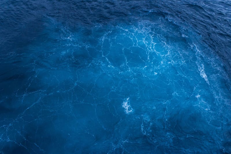 Capture of vibrant blue ocean waters with swirling patterns, viewed from above.