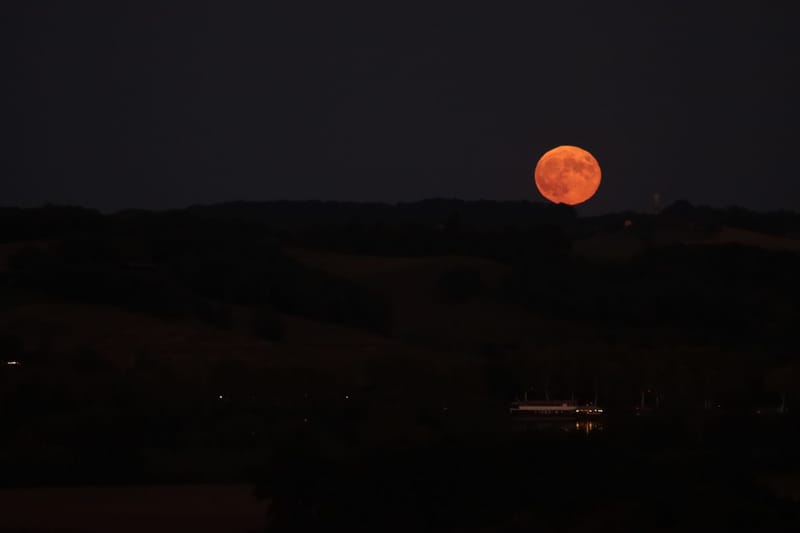 Captivating view of the full moon illuminating a serene landscape under a dark night sky.
